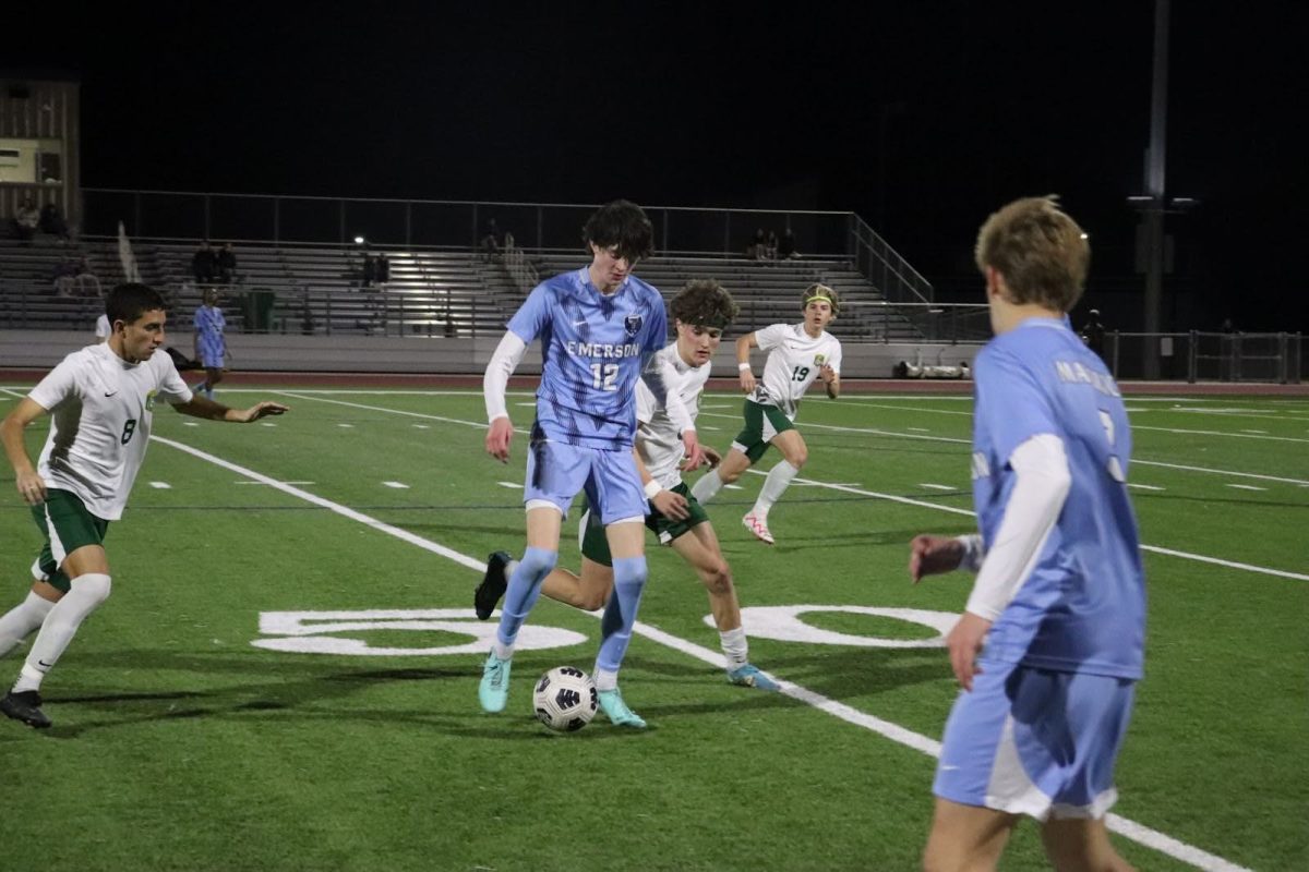 Junior Aden Mathews avoids two opponents at the same time as he rallies the ball away.