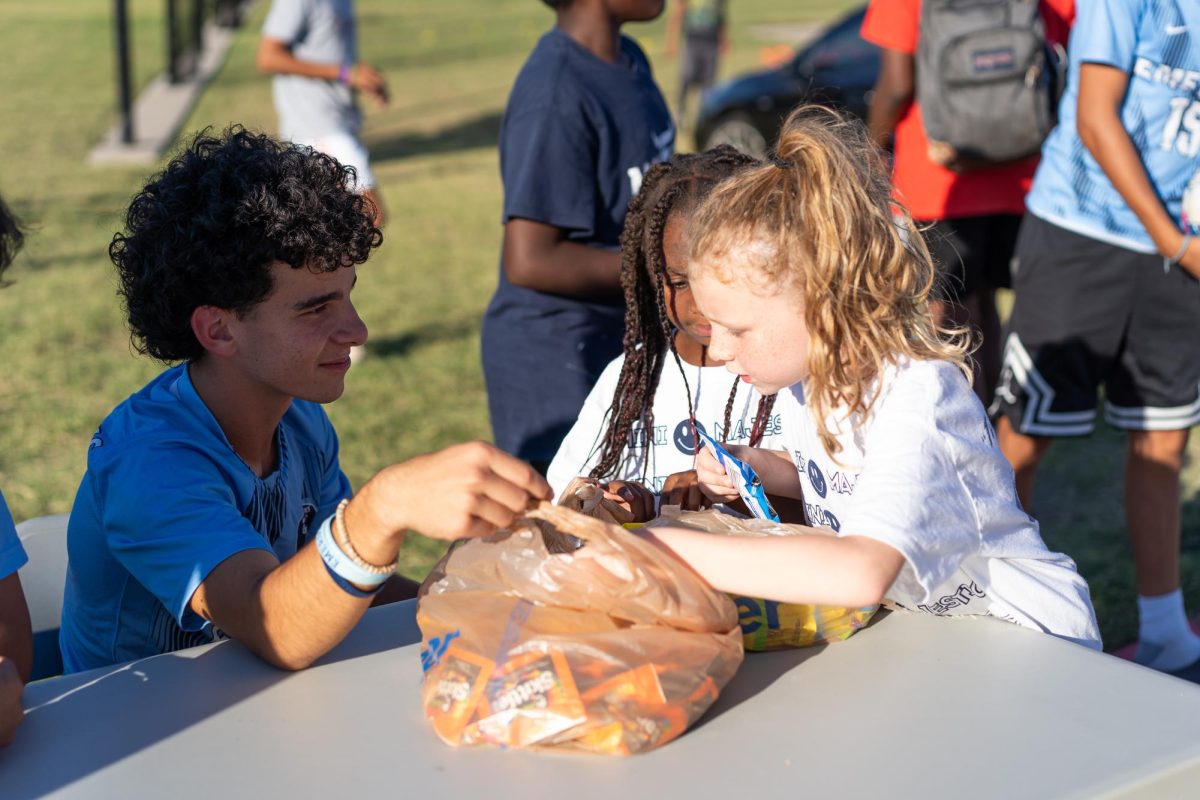 John Pacheco, 11, helps a young Maverick choose her prize at the soccer booth.