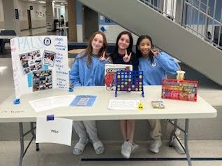 Chloe Gill, 12, Bailee Howell, 12, and Saniya Allen, 12, volunteer at the PALs booth.