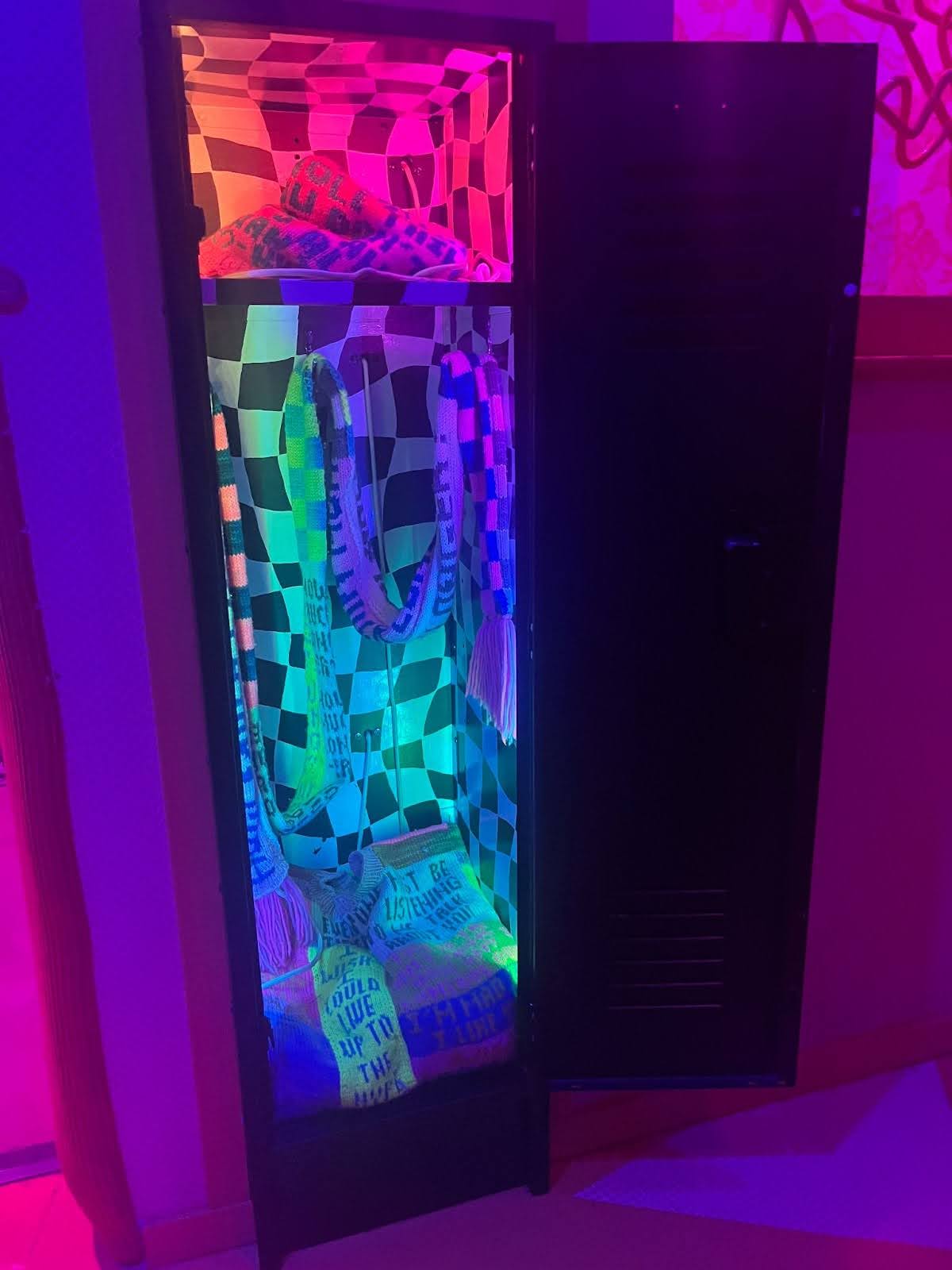 A locker embedded in a staircase in the Factory Obscura exhibit. When opened, it contains an illusionary checkered backdrop with streamers, knitting materials, and beads. Every piece of material holds a wish or a regret from a few of the collaborators.