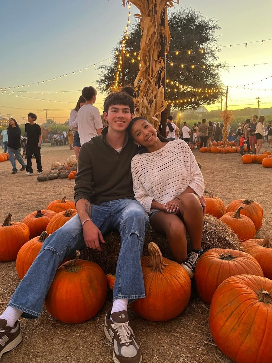 Allen and Canfield pose for a picture atop a collection of pumpkins and hay.