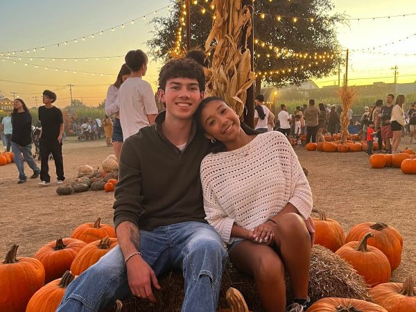 Allen and Canfield pose for a picture atop a collection of pumpkins and hay.