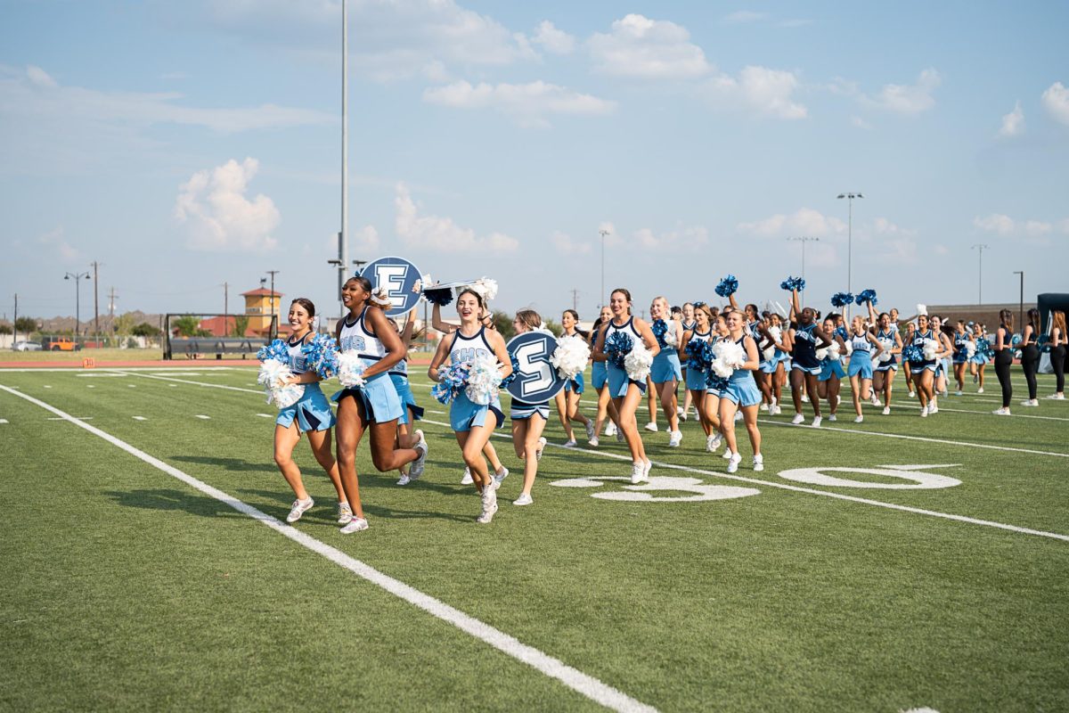 Emerson High School Cheerleaders sprint across football field and excite pep rally audience.