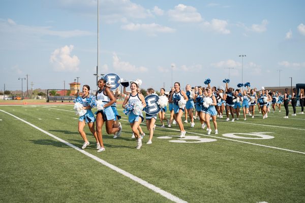 Emerson High School Cheerleaders sprint across football field and excite pep rally audience.