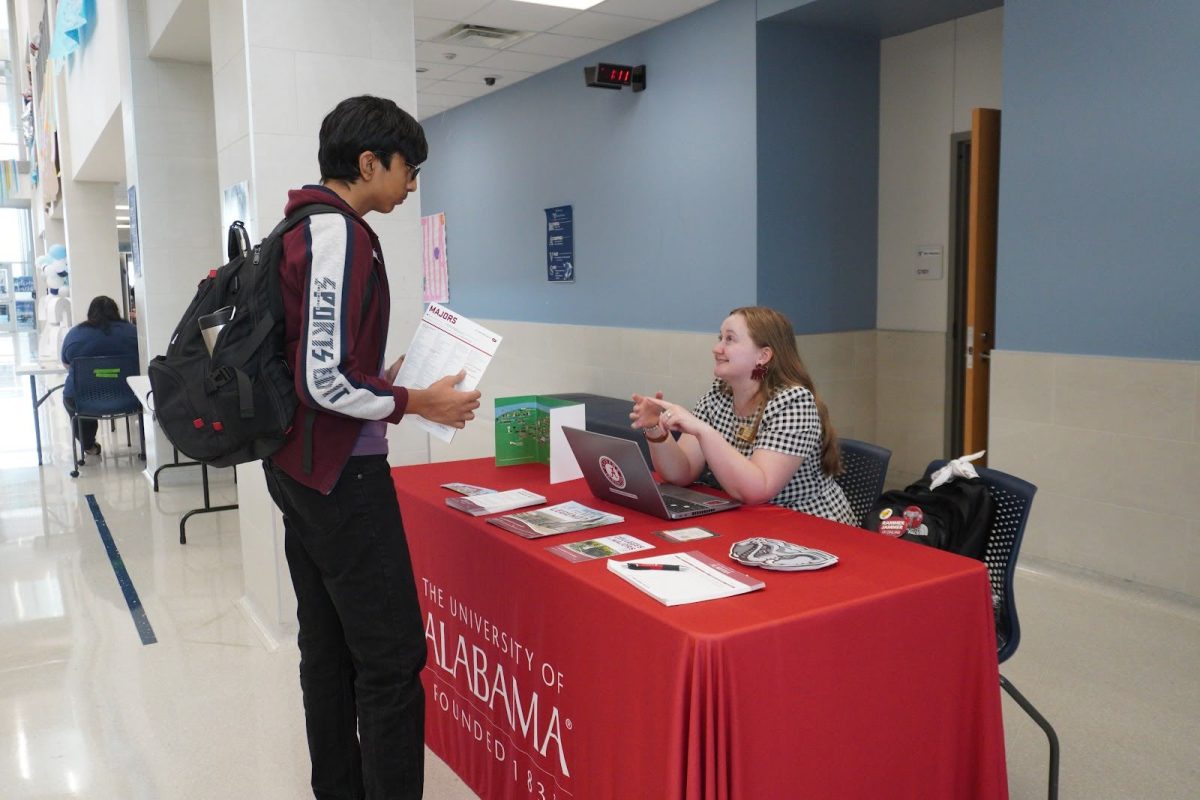 A student actively asks college-specific questions to the University of Alabama representative during the visit.